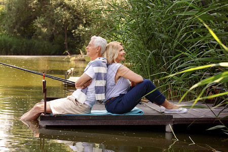 老夫妇背靠坐在码头上快乐的老年人在钓鱼图片