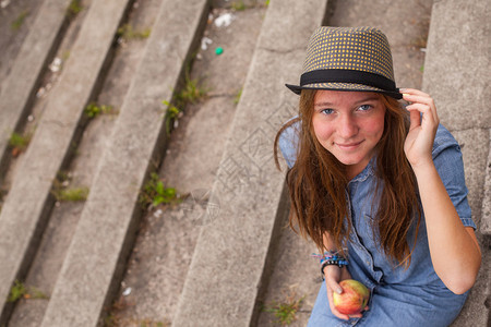 美丽的时髦年轻女孩戴着帽子坐在公园图片