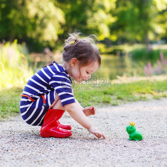 穿着红雨靴的可爱小公主女孩玩橡皮玩具青蛙户图片