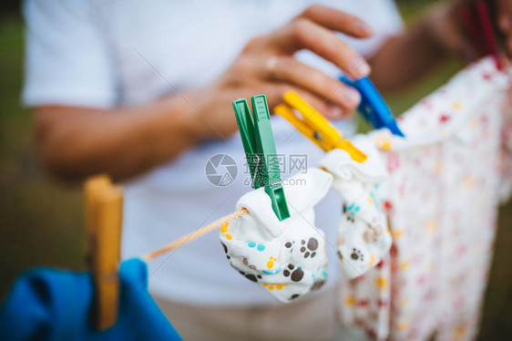 爸手把新生婴儿的衣服挂在绳子上在前头图片