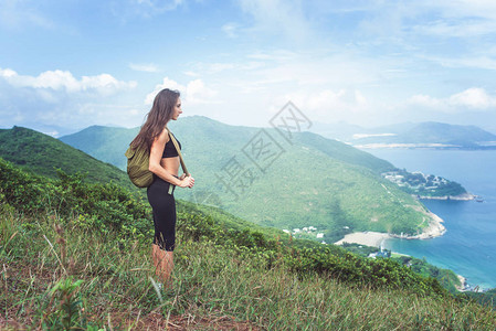 背包女旅行者站在山上看海山图片