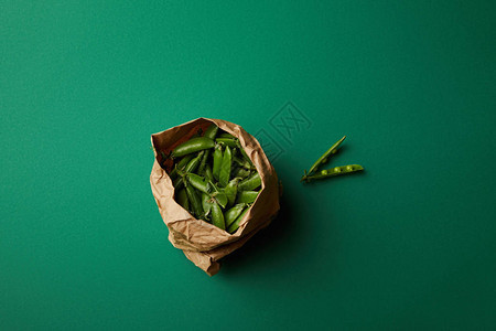 绿色表面有豌豆荚的纸袋顶视图背景图片