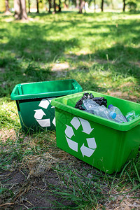 草地上放着垃圾的绿色回收箱图片