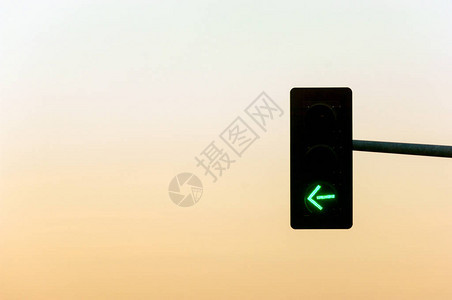 十字路口的红绿灯背景是绿灯箭头和日落图片