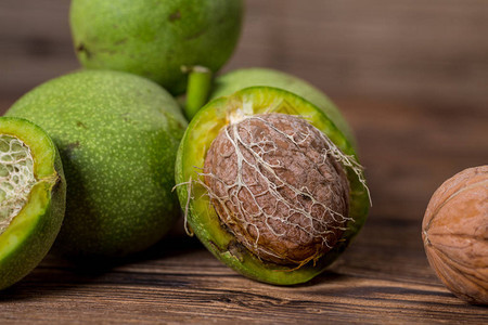 新鲜收获的核桃木制背景上绿色和棕色坚果核桃壳和果皮木质图片