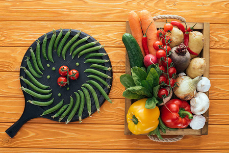 圆板上新鲜绿豆和西红柿木制桌顶箱图片