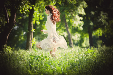 红发女人光着阳光照耀着光亮穿着优雅的礼服赤脚图片素材