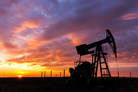 工业油气井轮廓日落时在风暴云图片