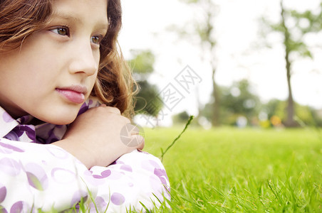 一个年轻女孩躺在公园绿草地上的近距离肖像图片