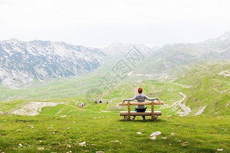 女孩正坐在山风景的长凳上公园杜米托尔图片