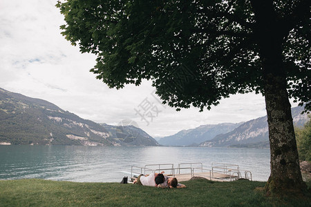 在瑞士伯尔尼山湖附近的绿草上一起躺在一对相亲爱图片