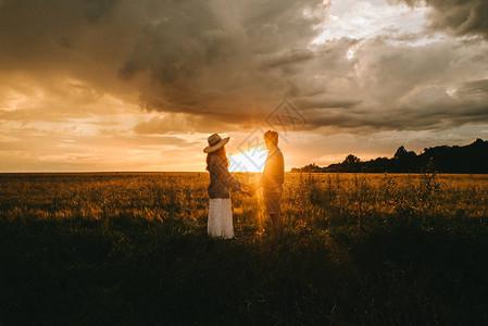 小情侣在日落时手握草地和爱情图片