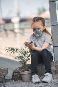 儿童在保护面罩中与绿锅植物接触空图片