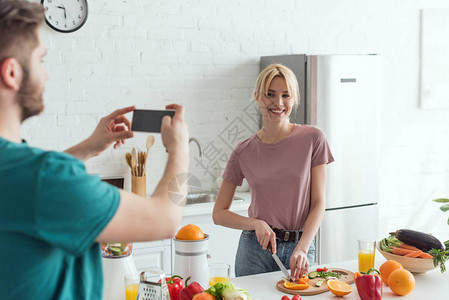 男人对在家里厨房做饭时微笑的女友烹饪片面照片的部分看法图片