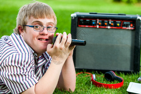 残疾人男孩用麦克风和扩音器在户外唱歌图片