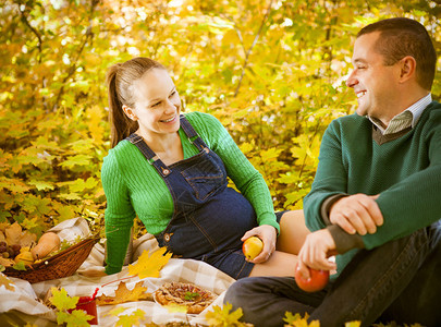 在秋天公园野餐的孕妇夫背景图片