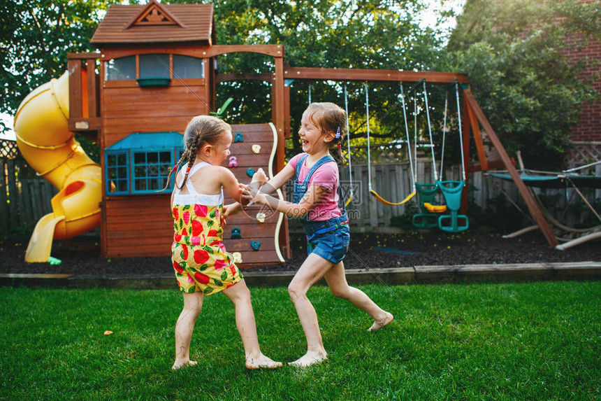 两个小女孩姐妹在家后院打架的画像朋友女孩玩得开心兄弟姐妹争吵在一起玩耍的生活方式坦图片