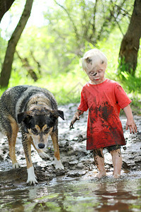 一个小男孩和他的德国牧羊人混杂狗被泥土覆盖图片