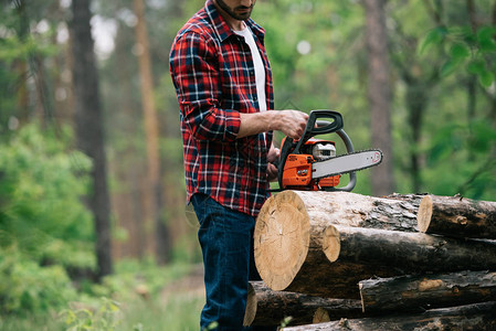 伐木工人在森林里用电锯切割圆木的剪影图片