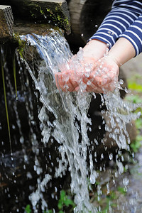 女性洗脸泼水水倒在自然背景上的女人手上背景