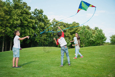多种族儿童在公园绿草坪玩风筝并参加盛大图片