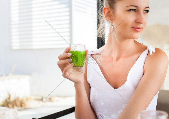 女人手里握着绿色果汁的杯子早上吃早餐时图片