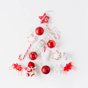 由圣诞舞会糖果白色背景的玩具组成的明亮红色圣诞树创造安排图片