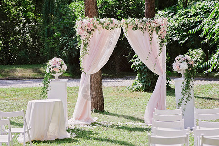 婚礼仪式的拱门在树前装饰着布图片