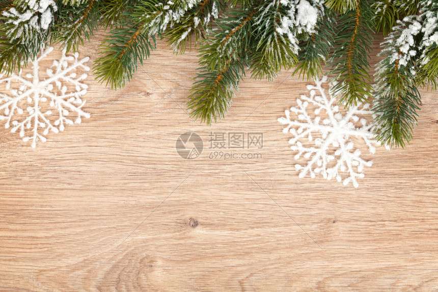 木板背景上覆盖着雪的圣诞树图片