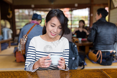 女人在日本餐厅享用热绿茶图片
