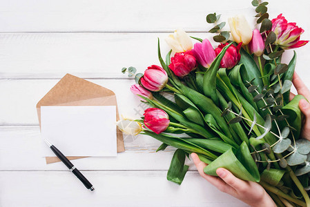 妇女手持郁金香花束用纸和笔打开信图片