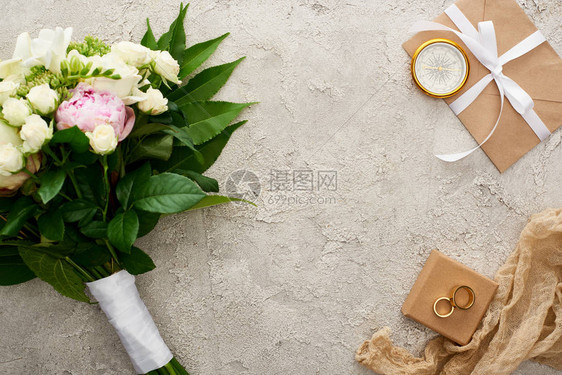 金罗盘米花麻布礼盒上的结婚戒指和包上贴有白色丝带的彩衣图片