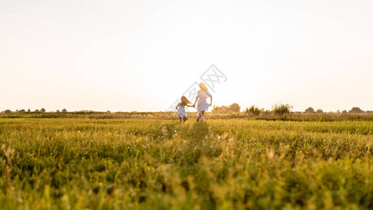 母亲和女儿在绿草地上奔跑图片