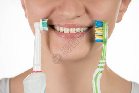 口腔卫生一个年轻漂亮的女孩在电动和简单的牙刷之间做出选图片
