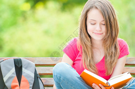 坐在长凳上微笑和阅读书上图片