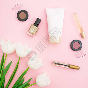 粉红色背景上带有化妆品的嫩郁金香花的顶视图图片