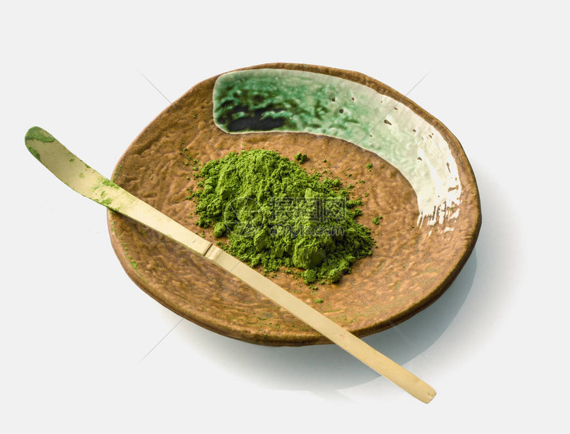 白色背景的陶瓷粘土板上的日本火柴加绿色茶粉和竹匙用于在茶叶仪式期间用碗把图片