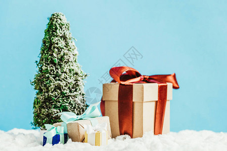 近距离拍摄圣诞礼物和小型圣诞树在蓝底雪图片