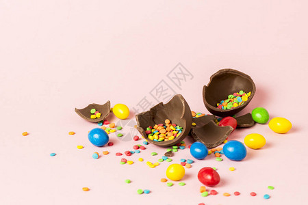 碎复活节巧克力蛋和粉红背景的多色糖果复活节图片