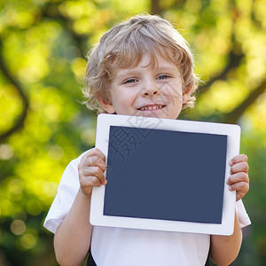 拥有平板电脑户外用品的可爱快乐的小孩图片