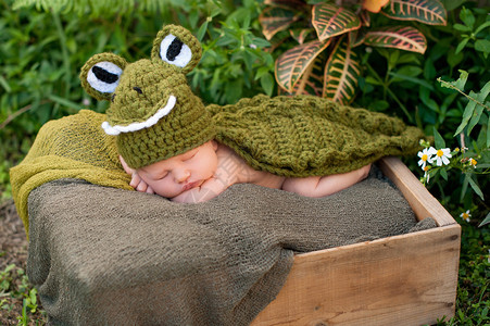 一个8天大的新生男孩穿着绿色鳄鱼服他睡在一个箱子里图片