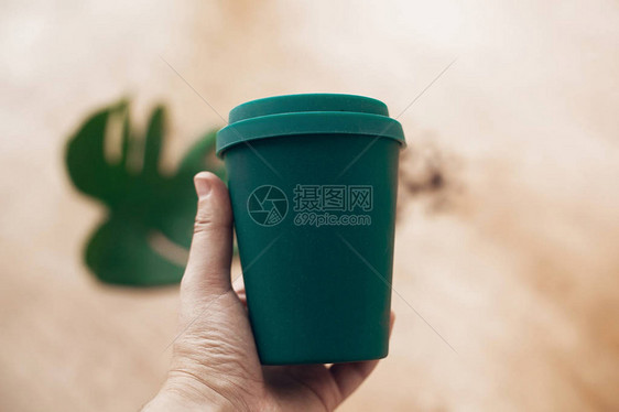 禁止使用一次塑料手拿着生态可重复使用的咖啡杯木制背景竹纤维咖啡杯图片