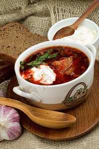 乌克兰全国传统汤用甜菜蔬菜和肉用木勺在木盘上安排红面包大蒜和酸图片