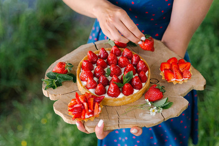 在锯木板上持有草莓蛋糕和小草莓背景图片