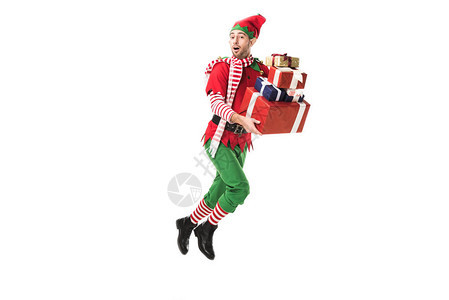 穿着圣诞精灵服装的男子惊讶地跳跃并携带一堆礼物图片