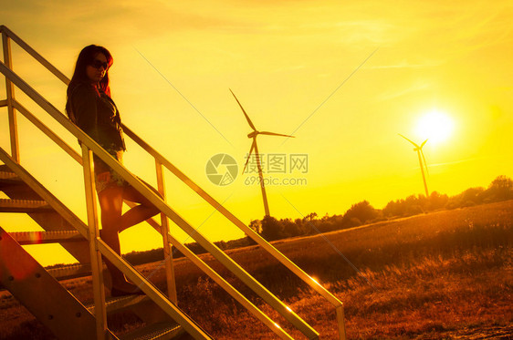 女孩站在楼梯上在惊人的日落中向图片