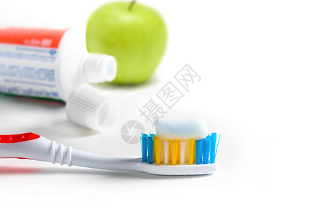 牙刷与挤压糊特写镜头牙膏管和白色背景上的青苹果图片
