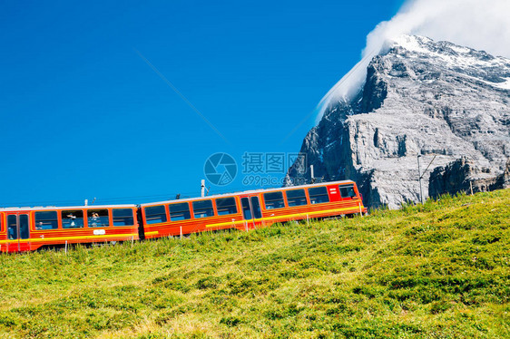 红列车和雪山在瑞士丛林图片