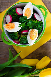 带西兰花鸡蛋和萝卜的沙拉在小碗里放在木质背景和图片