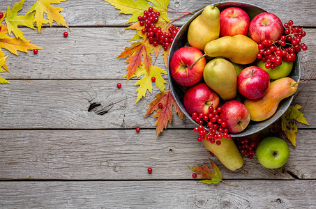 旧金属盆中的各种水果罗文苹果梨和风化质朴木材上的落叶图片